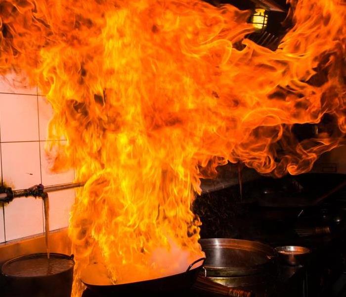 Flames coming from cooking pan on a stove.