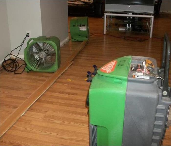 Air movers and dehumidifier placed on floor of a basement drying out walls and floors